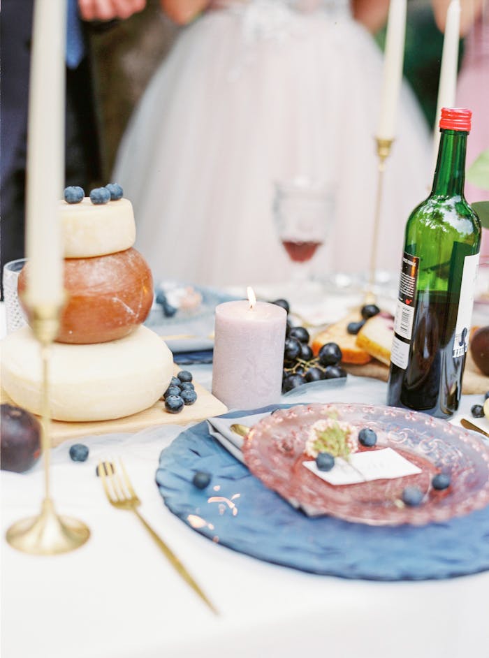 portfolio-06 Wedding table setting featuring cheese, wine, blueberries, and candles for an elegant celebration.