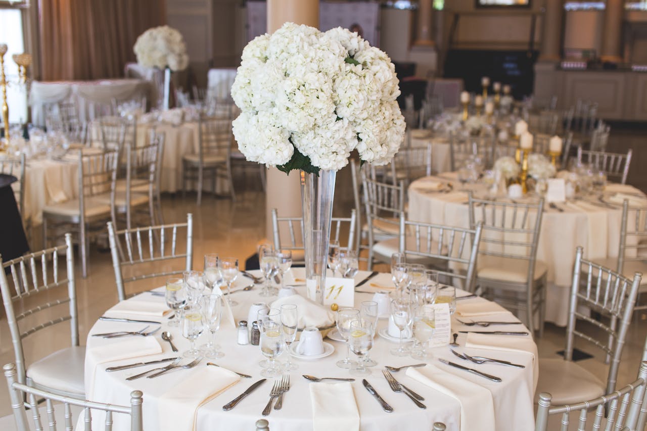 why-choose-us Beautifully decorated wedding reception table with elegant floral centerpiece and silverware.