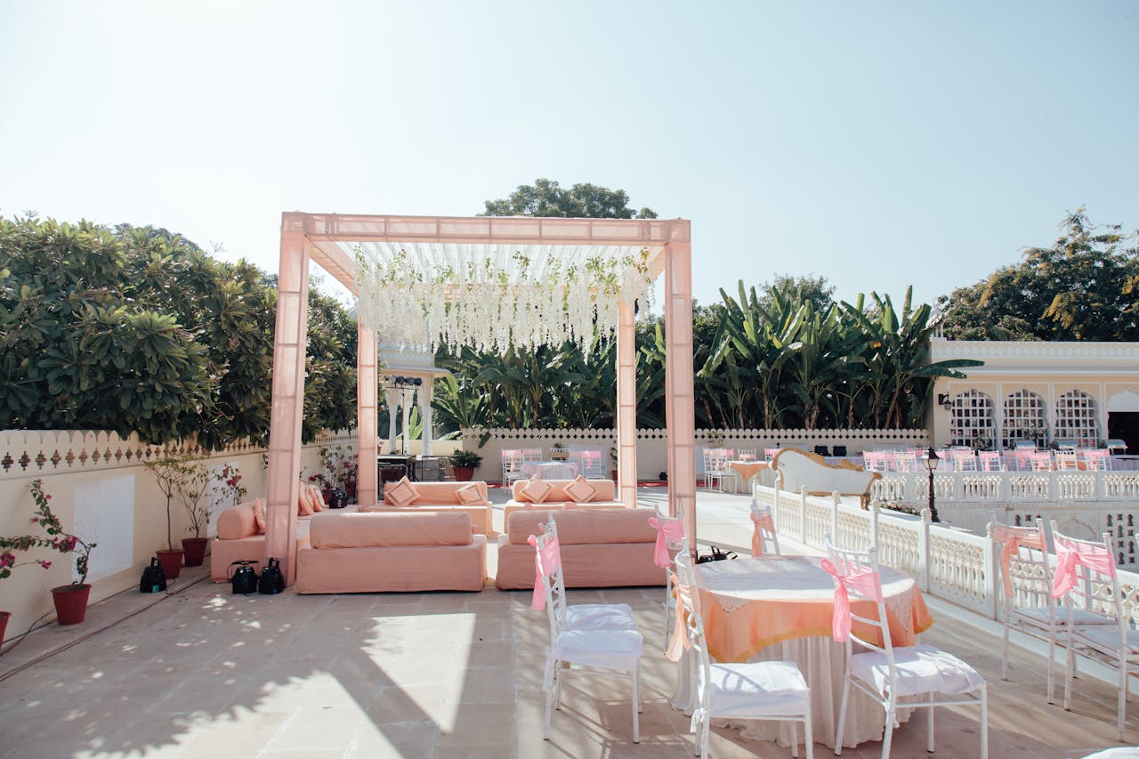 portfolio-05 Beautiful outdoor wedding setup with pink decor and floral arrangements under clear skies.